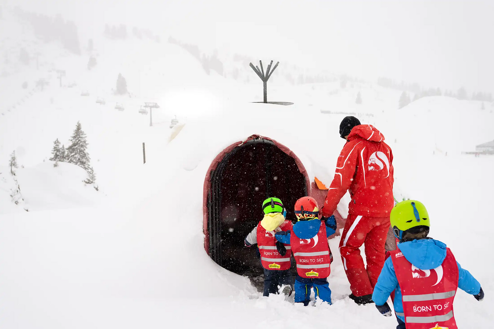 Eine Gruppe Skikurs-Kinder geht durch einen Tunnel im Kinderland